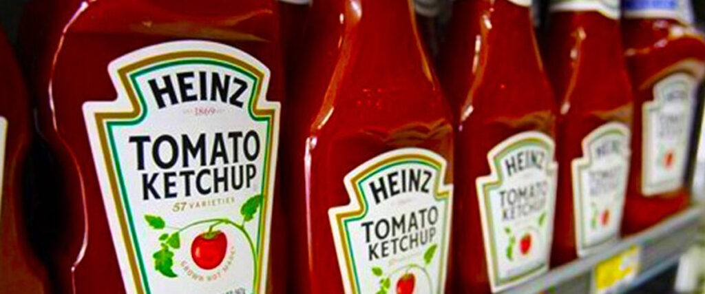 Several bottles of Heinz Tomato Ketchup are lined up on a store shelf. Each red bottle features the recognizable Heinz label with "57 varieties" written below the logo, and a picture of a red tomato above the words "Tomato Ketchup," making it perfect for your next presentation slide.