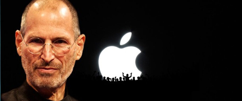 A man with glasses and a serious expression stands against a dark background with a large, illuminated Apple logo and a crowd of silhouettes, as if presenting the ultimate pitch deck.