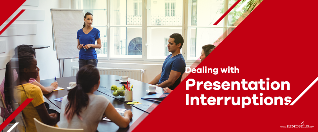 A group of people in a meeting room listens to a standing presenter in front of a flip chart. The red text overlay reads, "Dealing with Presentation Interruptions." Cups and notebooks are on the table, along with a presentation slide template, and a window is in the background.