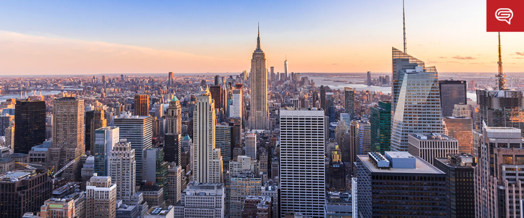 A panoramic view of a city skyline at sunset, featuring a mix of modern skyscrapers and iconic buildings under a soft, colorful sky. The light on the buildings varies from golden to shadowed, adding depth to the vista, making it perfect for enhancing your PowerPoint presentation.