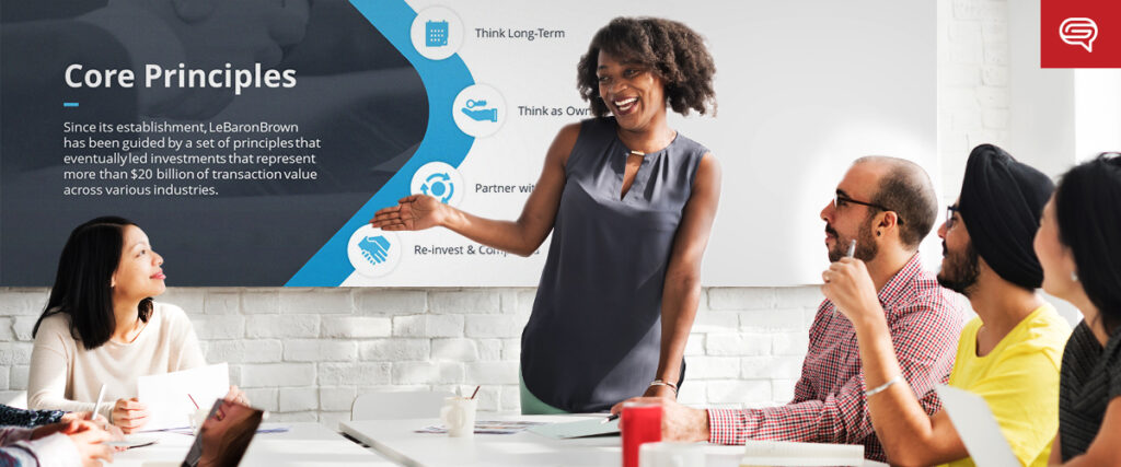 A diverse group of professionals sits around a conference table, attentively listening to a smiling woman presenting. Behind her, a large screen displays a slide titled "Core Principles" with several bullet points: "Since its establishment, LeBaronBrown has been guided by principles that led investments over $30 billion across various industries." The atmosphere appears collaborative and focused, enhanced by an effective pitch deck.