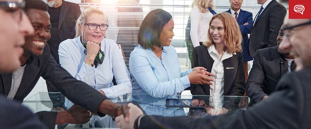 A diverse group of professionals sits around a glass table in a well-lit conference room, engaged in animated conversation and smiling. The scene unfolds like a lively flipbook, with some people shaking hands, indicating a friendly and collaborative atmosphere.