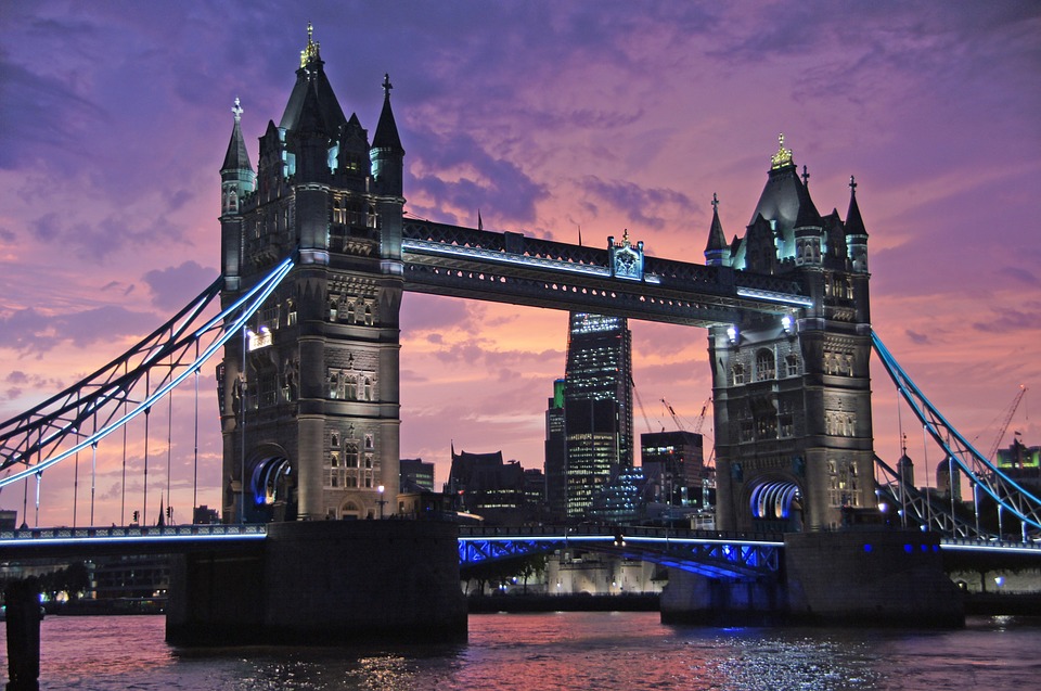 The image showcases London’s iconic Tower Bridge illuminated at dusk, with a SlideGenius touch. The sky is a vibrant blend of purple and pink hues, the city skyline visible in the background, reflecting beautifully on the Thames River below.