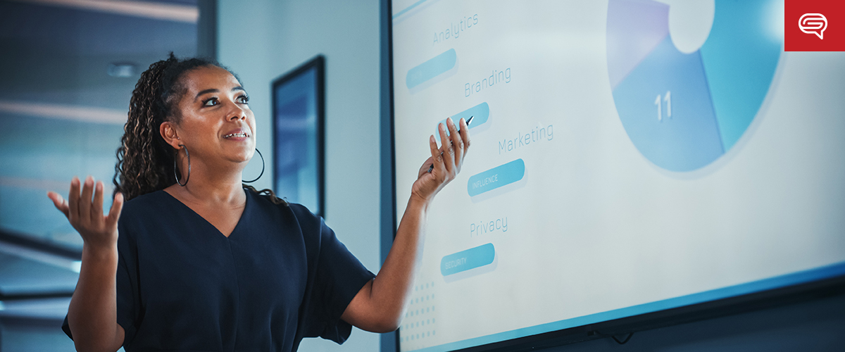 A woman gestures while presenting data on a large screen, showcasing sections and a pie chart labeled with words like "Branding" and "Marketing." This client experience slide is tailored for consulting firms seeking to enhance their strategic insights.